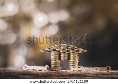 Stack gold coin into a house shape with growing interest value and a wrench and construction tool with repair put on the wood in the public park, Loan and business investment for real estate concept.