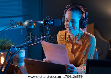 Young smiling radio presenter talking into the microphone and reading news, information and communication concept