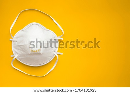 White face medical mask against virus, flu and coronavirus isolated on  orange background. Protective respirator with valve. Royalty-Free Stock Photo #1704131923