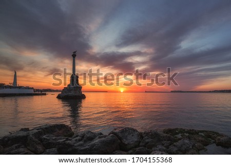 Beautiful sunset on the embankment of Sevastopol. The symbol of Sevastopol is a Monument to sunken ships, a historical memorial. The sun sets in the sea. Sevastopol, Crimea. Royalty-Free Stock Photo #1704155368