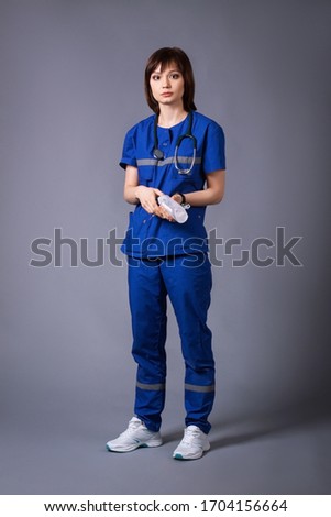 Portrait of a young nurse. Girl holds a dropper in her hands posing on a gray background in the studio during a photo shoot. Royalty-Free Stock Photo #1704156664