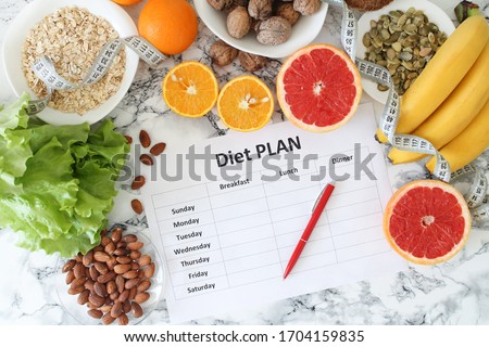 Healthy eating, dieting, slimming and weigh loss concept - closeup of diet plan paper with fruit, nuts and centimeter.