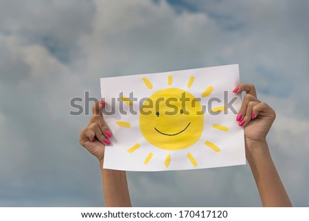 human hands with sheet of paper with sun image against overcast sky - positive thinking concept