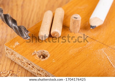 Installation of chipboard with carpentry dowels and glue. Small work in a carpentry workshop. Light background.