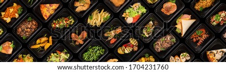 Collection of black plastic take away boxes with healthy food. Set of containers with everyday meals - meat, vegetables and law fat snacks on black background Royalty-Free Stock Photo #1704231760