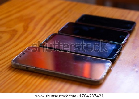 Angle view of four cellphones by size order with colorful reflection on screen. Mobile devices old and new generation, communication, technology concepts