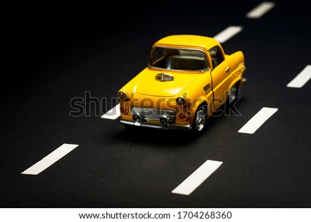 Front view of a Yellow toy car on on an asphalt road