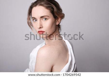 Beauty portrait of young woman with red lips wearing white clothing. Close-up portrait. Space for text.