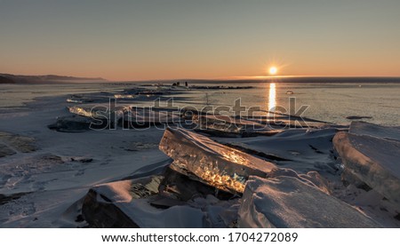 The Baikal Lake in winter with a surface covered with a thick layer of transparent cracked ice and ice hummocks at sunrise - Siberia, Russia