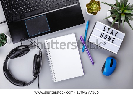 Light box with text STAY HOME, laptop, notepad on gray background. Healthcare and medical concept. Coronavirus, Quarantine and isolation concept. Covid-19, 2019-nCoV. Top view.
