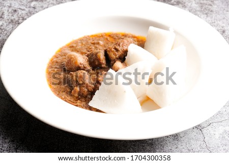 A selective focus picture of "kuah kacang" or peanut sauce with "nasi impit" or pressed rice. Traditional Malay Nusantara food usually serve during Eid or snack.