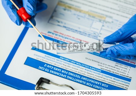 Medical worker holding swab sample collection kit,test tube for performing patient nasal swabbing,hand in gloves holding testing equipment over specimen submitting form,Coronavirus COVID-19 diagnostic Royalty-Free Stock Photo #1704305593