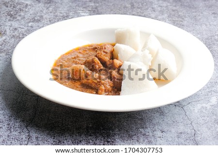 A picture of "nasi impit" or pressed rice with "kuah kacang" or peanut sauce. Traditional Malay Nusantara food usually serve during Eid or snack.