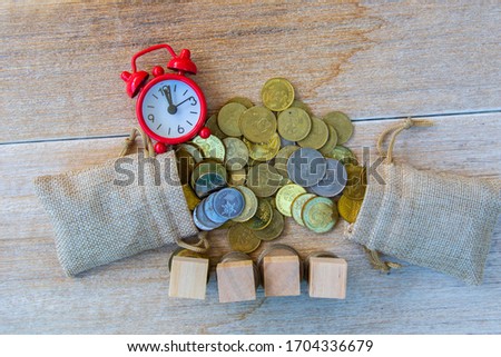 sack bag, Malaysia Ringgit coin , red alarm clock and blank wooden block on wooden table.- Saving Concept