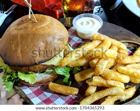 Chicken schnitzel burger bun served with fries or potato chips and aioli sauce.