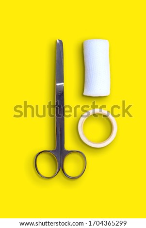 Scissors, bandages and band-aid on yellow background, top view, medicine concept, flatlay