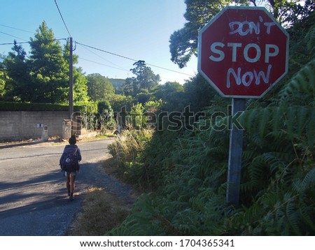 Pilgrim and road sign with written "Don't Stop Now", Camino de Santiago, Way of St. James, Journey from Teo to Santiago de Compostela, Portuguese way, Spain