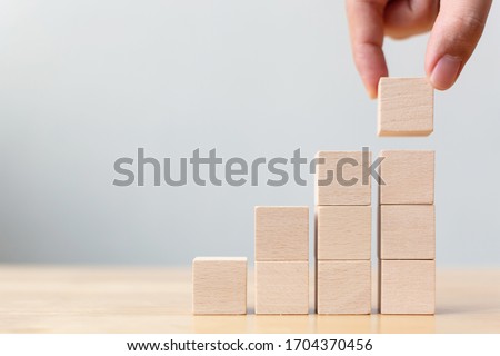 Hand arranging wood block stacking as step stair on wooden table. Business concept for growth success process. Copy space Royalty-Free Stock Photo #1704370456