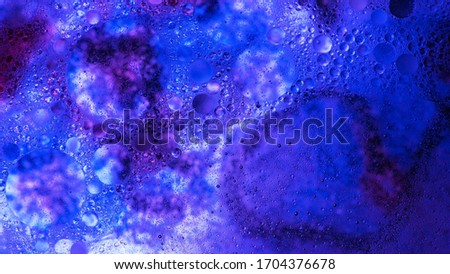 Mixing water and oil, beautiful colors. Blue light. Close-up. Abstract macro background. Water and oil bubbles. Abstract light illumination