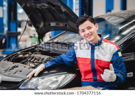 Pictures of an Asian car mechanic smiling comfortably in his garage. Car service including repair centers and car repair centers.