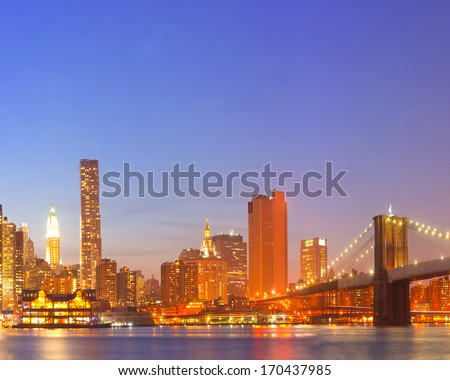New York City  USA, lights on the buildings in lower Manhattan are reflected in the water during colorful sunset