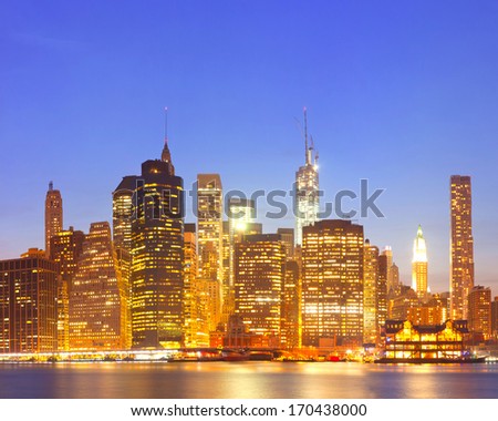 New York City  USA, lights on the buildings in lower Manhattan are reflected in the water during colorful sunset