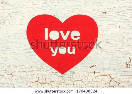 Paper heart with the word love you on old wooden door