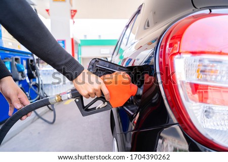 Refuel cars at the fuel pump. The driver hands, refuel and pump the car's gasoline with fuel at the petrol station. Car refueling at a gas station Gas station Royalty-Free Stock Photo #1704390262