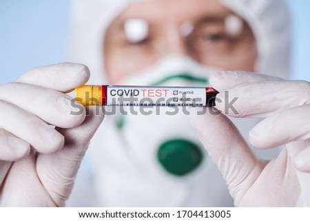 Doctor with a tube of biological sample contaminated by Coronavirus with label Covid Test. A breakthrough in the procedure. Pandemic.  Royalty-Free Stock Photo #1704413005
