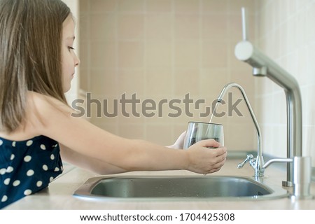 Girl using filter to purify drinking clean water. Kitchen faucet. Filling cup beverage. Infection viruses through tap water. Quality check. World water monitoring day. Environmental pollution concept Royalty-Free Stock Photo #1704425308