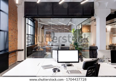 Computer with blank screen on the working place in the modern loft office