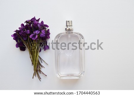 Perfume bottles and flowers on white background, top view. Flat lay arrangement with space for text. Mockup branding cosmetics. 