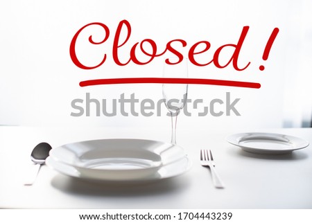 cutlery on the table, serving by the window in a restaurant. The word Closed - as a concept for closing public places and restaurants during a pandemic.