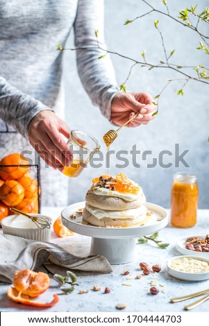 
Meringue cake with mandarins, nuts and figs. Light background. Meringue made of aquafaba. Vegan cake.