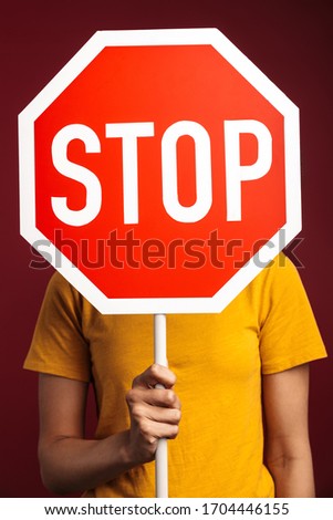 Image of outraged young brunette african american woman holding stop sign isolated over red background