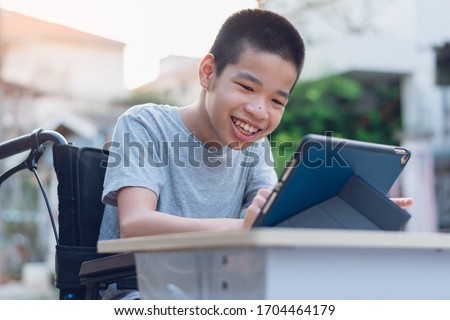 Disabled child on wheelchair happy time to use a tablet in the house, Study and Work at home for safety from covid 19, Life in the education age of special need kid, Happy disability boy concept. Royalty-Free Stock Photo #1704464179