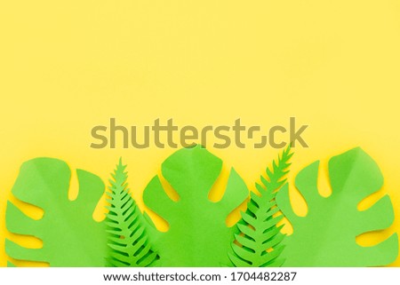 Paper tropical palm leaves on pastel yellow background. Minimal summer concept with a copy space.