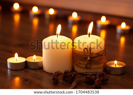 Aromatherapy flame closeup picture. Beautyful burning light yellow creme vanilla candles with wooden background. Evening spa lightens