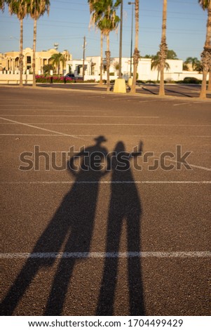 Shadows of man and woman are on asphalt. Big shadows of people on sunset on parking