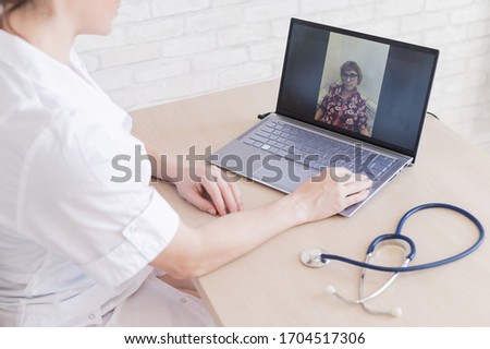 gp hosts an online appointment with an elderly quarantined patient at home. Female doctor at the desk talking to an elderly woman on a web camera and gives treatment recommendations