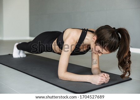 Photo of athletic beautiful woman in sportswear doing exercise while working out on mat