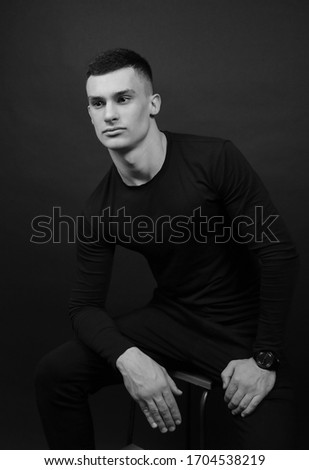 A handsome young guy. Beautiful brunette with a charming smile. Black and white photo of a handsome guy.