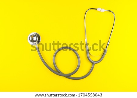 Stethoscope and heart shape isolated on yellow background.