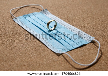 A wedding ring on a medical face mask. Divorce and marriage separation during the Coronavirus (covid-19) pandemic concept image.  Royalty-Free Stock Photo #1704566821