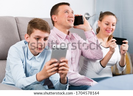 Parents and son happy to play with mobile phones together at home