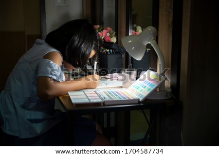 Asian children writing and using smartphone to doing homework at home.Happy Thai Kid drawing and painting with color pencil.Education concept
