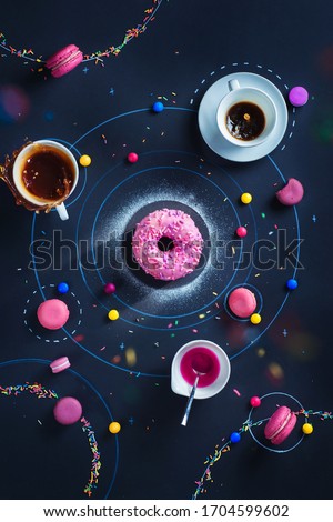 Creative food flat lay with space donut, macaron stars and orbits, falling sprinkles and tea splash Royalty-Free Stock Photo #1704599602