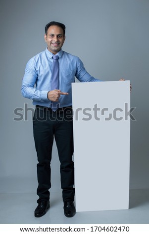 Happy attractive businessman holding blank billboard as copyspace 