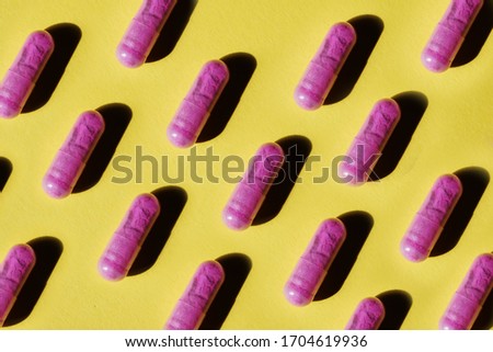 Pattern of purple pill capsules on a yellow background. Background and texture for the concept of unusual abstract medicines for the treatment of diseases and symptoms