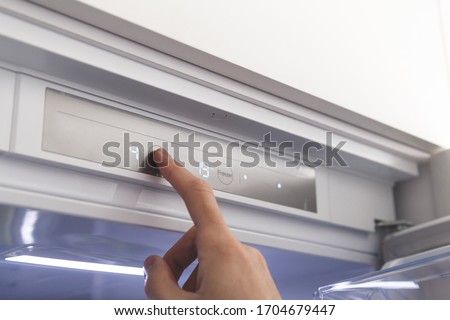 Hand sets temperature of refrigerator Royalty-Free Stock Photo #1704679447